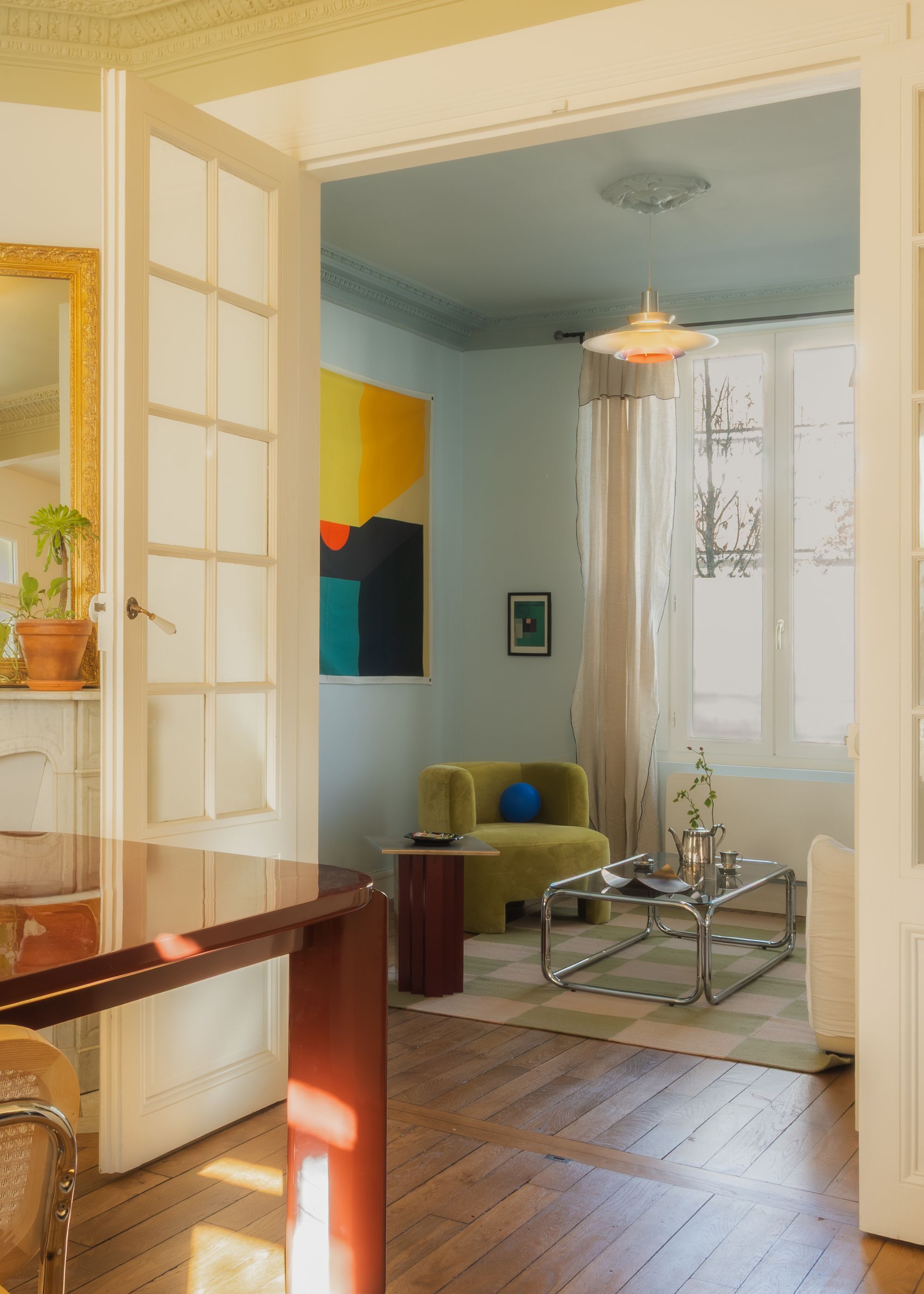 A dining-cum-living room with wooden flooring and soft pastel hues