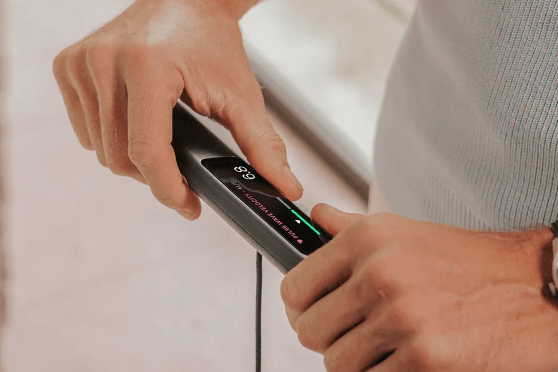 Close-up of hands holding the BodyScan 2's retractable handle, which has a small display.