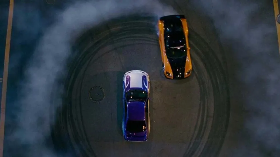 A car doing donuts around another car in The Fast and the Furious: Tokyo Drift