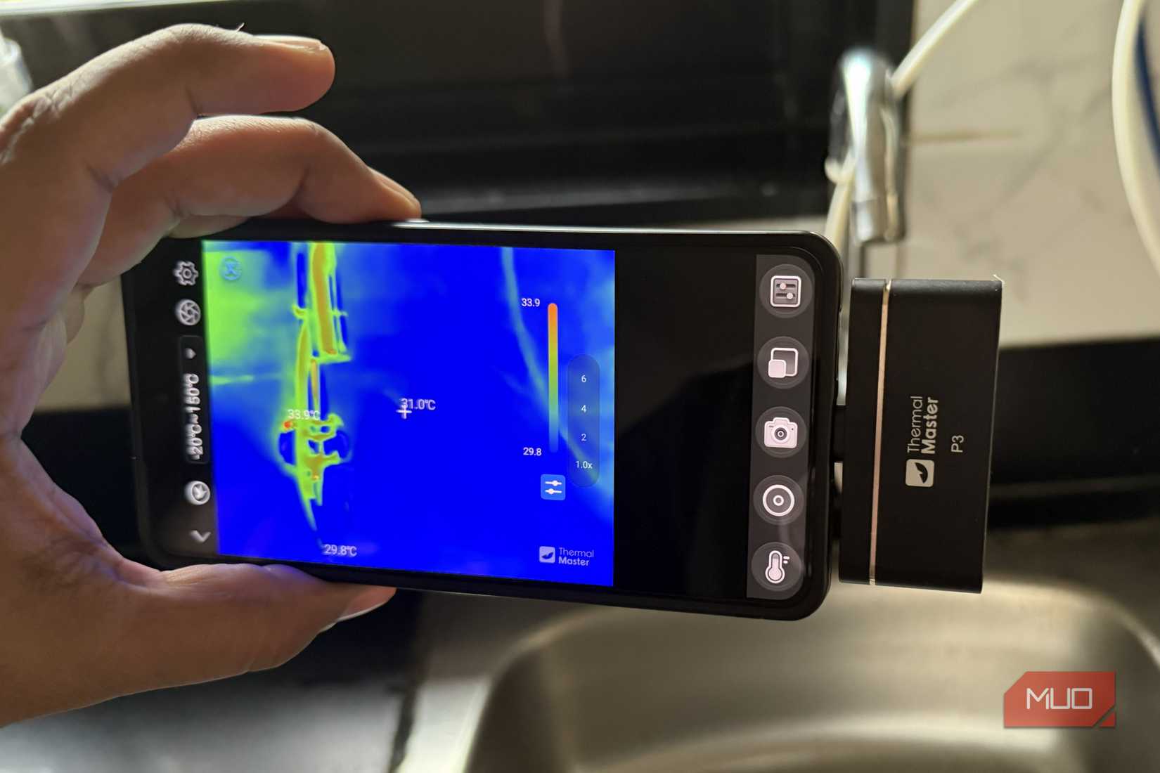 A phone connected to a thermal camera pointing at kitchen sink