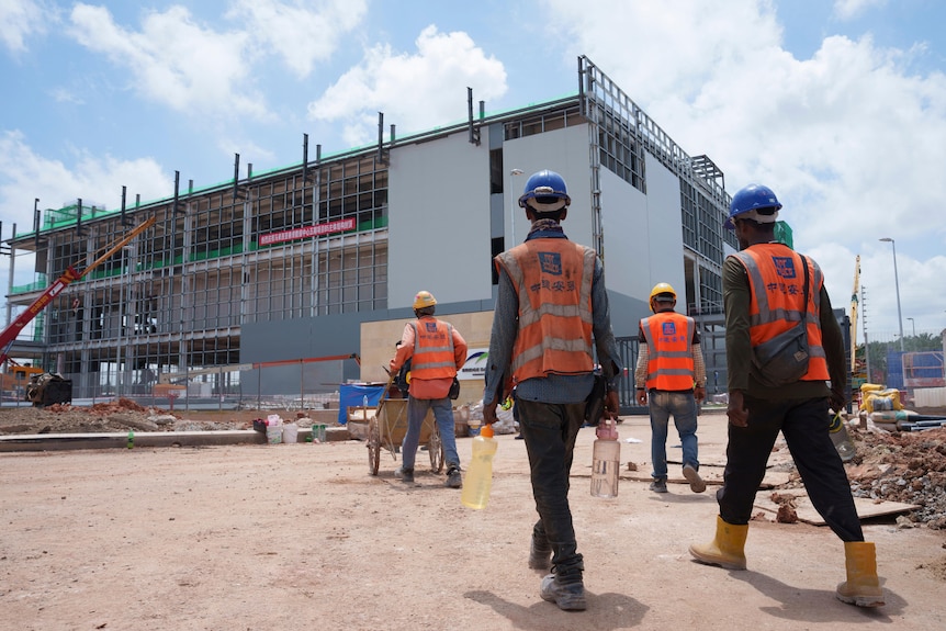 Workers in high-vis approach a construction site.