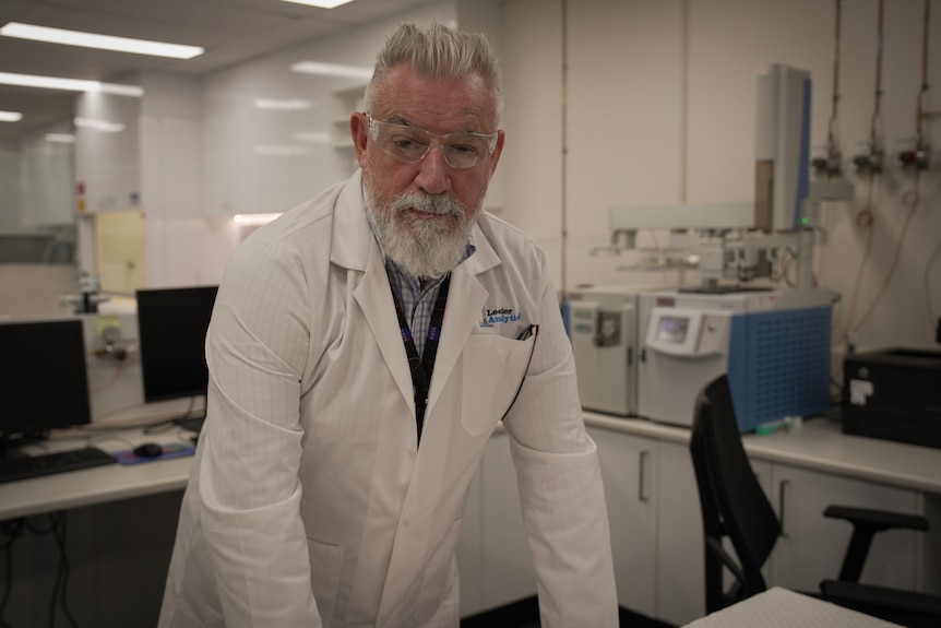 A man in a white lab coat standing in a laboratory.