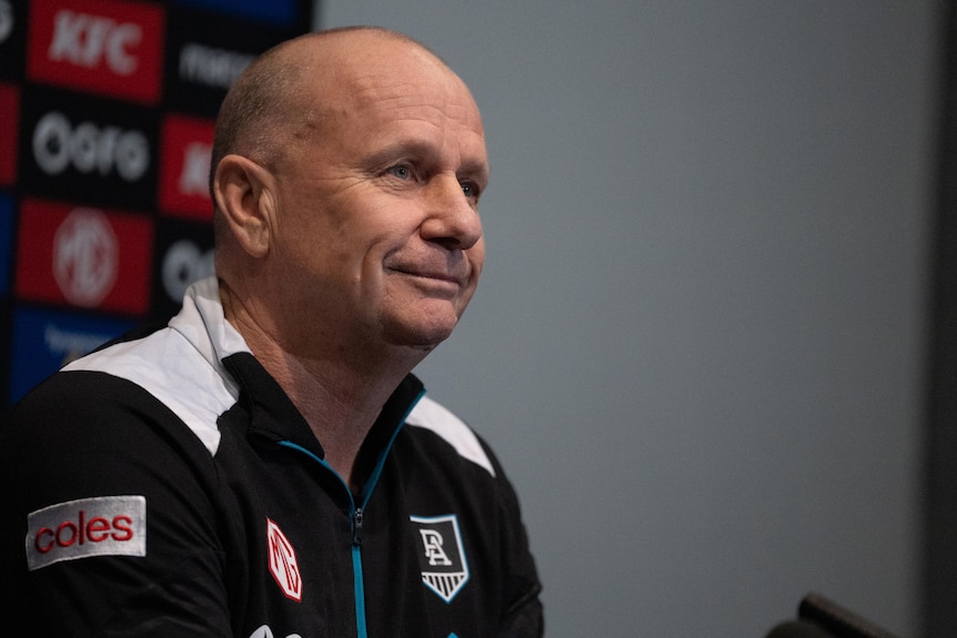 A sporting coach at a media conference.