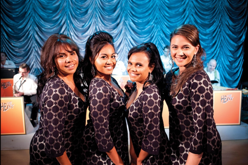 Deborah Mailman, Jess Mauboy, Miranda Tapsell and Shari Sebbens with bee hive hairdos on stage with a big band