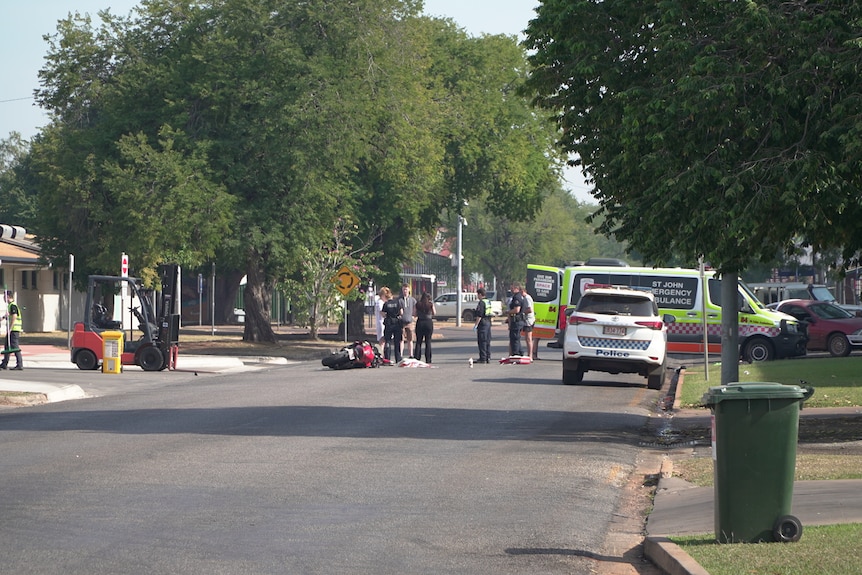 Emergency services surround a crashed red motorcycle on a public street.