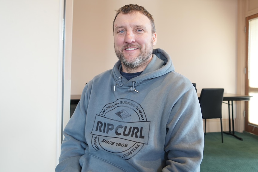 A man in a hoodie in a board room.