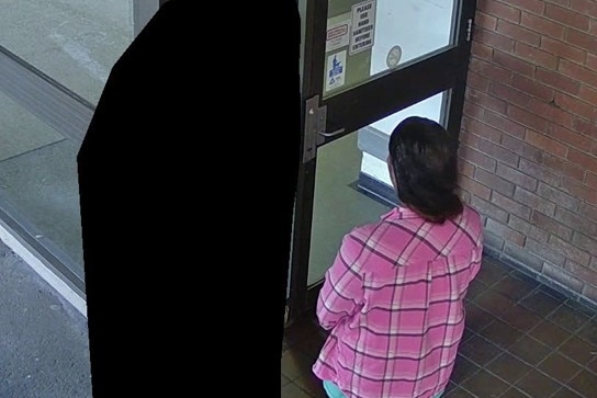 A woman and a person whose identity has been obscured outside a doorway.