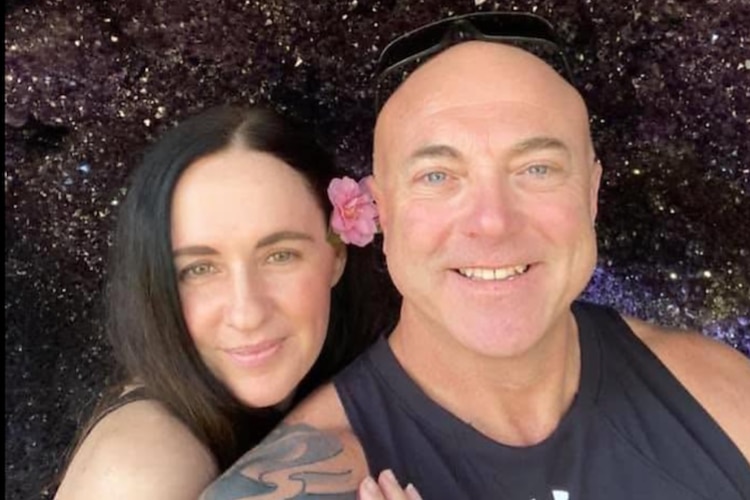 A woman with dark hair and a man with a black singlet and arm tattoos.