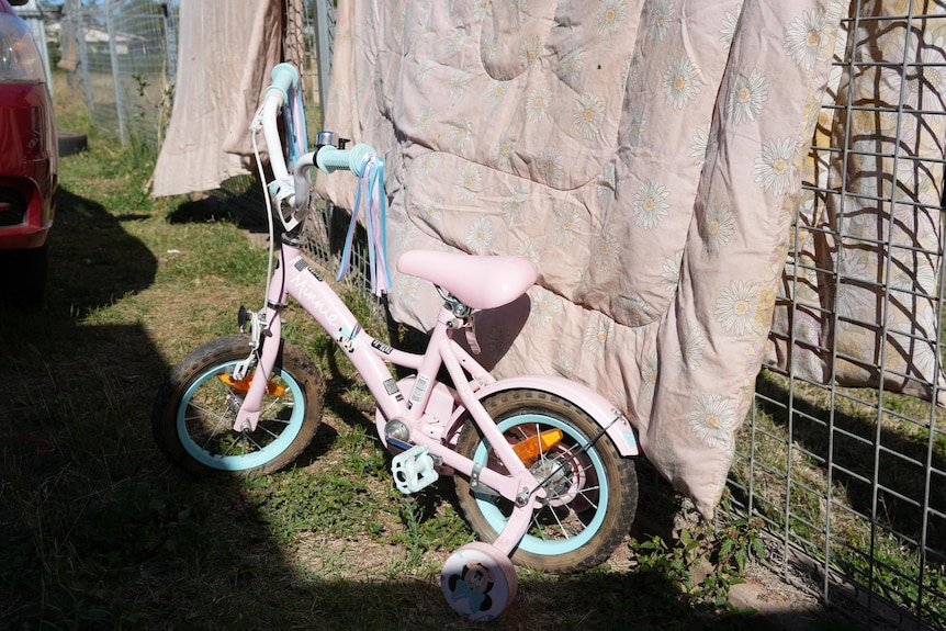 A small bike leaning against a fence.
