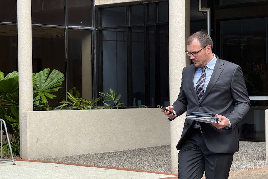 A man in a suit walking looking at his phone