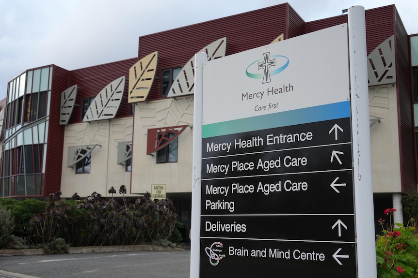 A sign in the fporeground of a picture of a health business complex