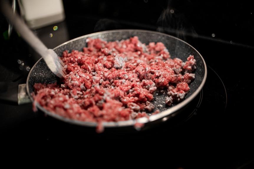 Red and brown mince meat cooking in a frying pan.