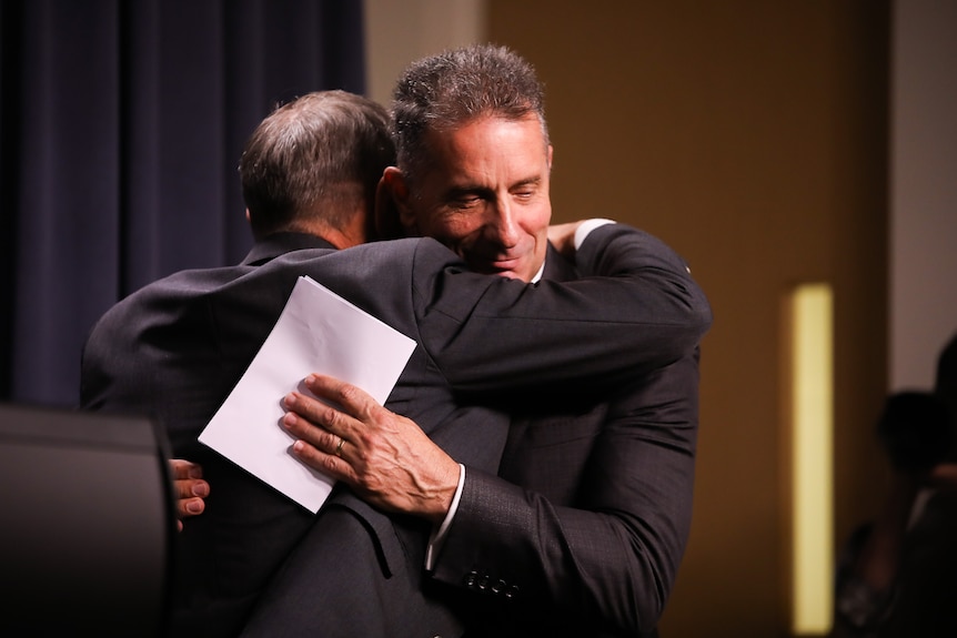 Two men in suits hug