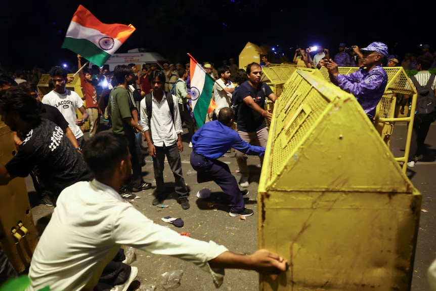 Crowds of people pushing barricades during a protest at nighttme
