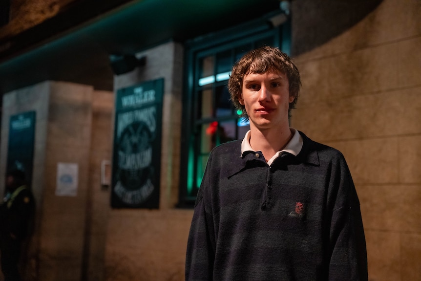 Young man standing in front of a sandstone building.