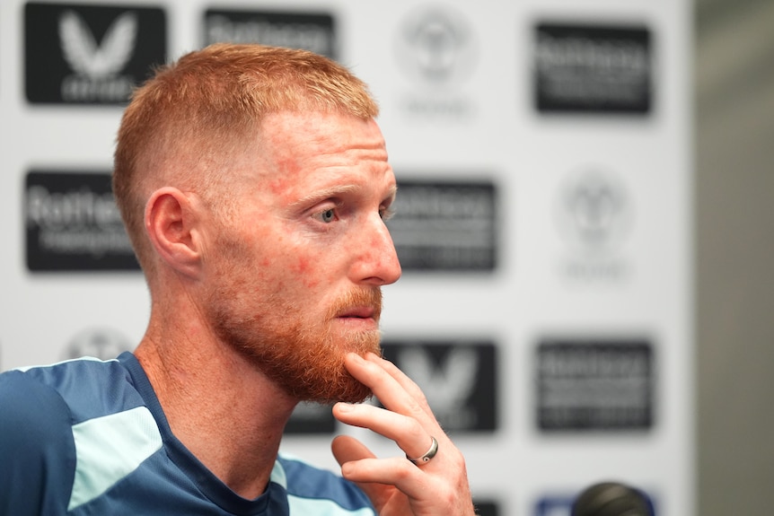 Ben Stokes holds his hand to his chin during a press conference.