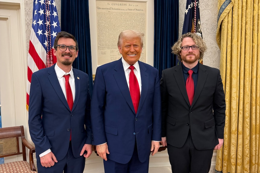 Two men standing with Donald Trump in the middle.
