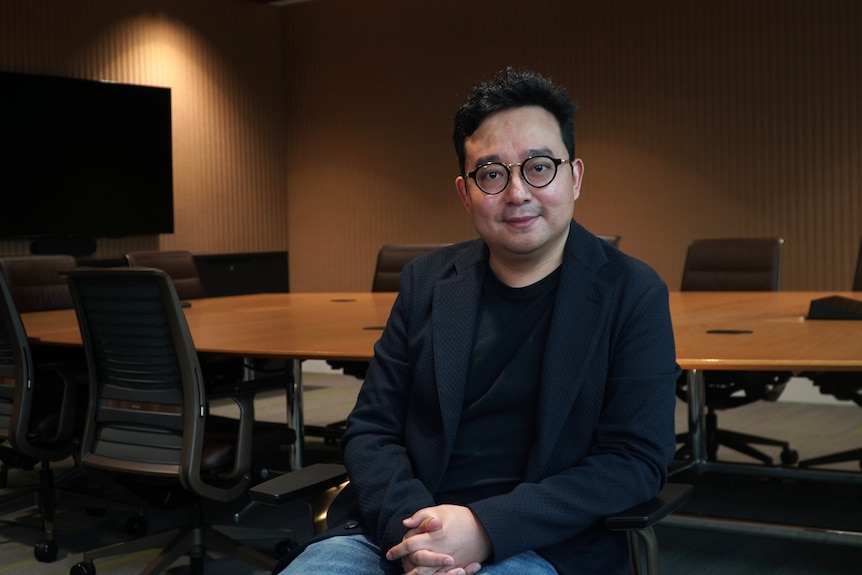 A man in a suit looks at the camera