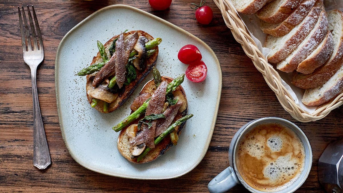 Anchovies on toast on a plate on a table.