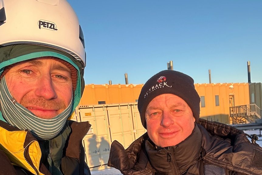 Two men taking a photo in the snow