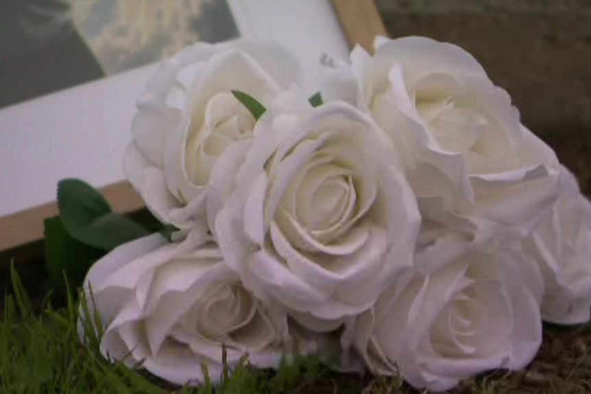 White roses placed next to a photo frame