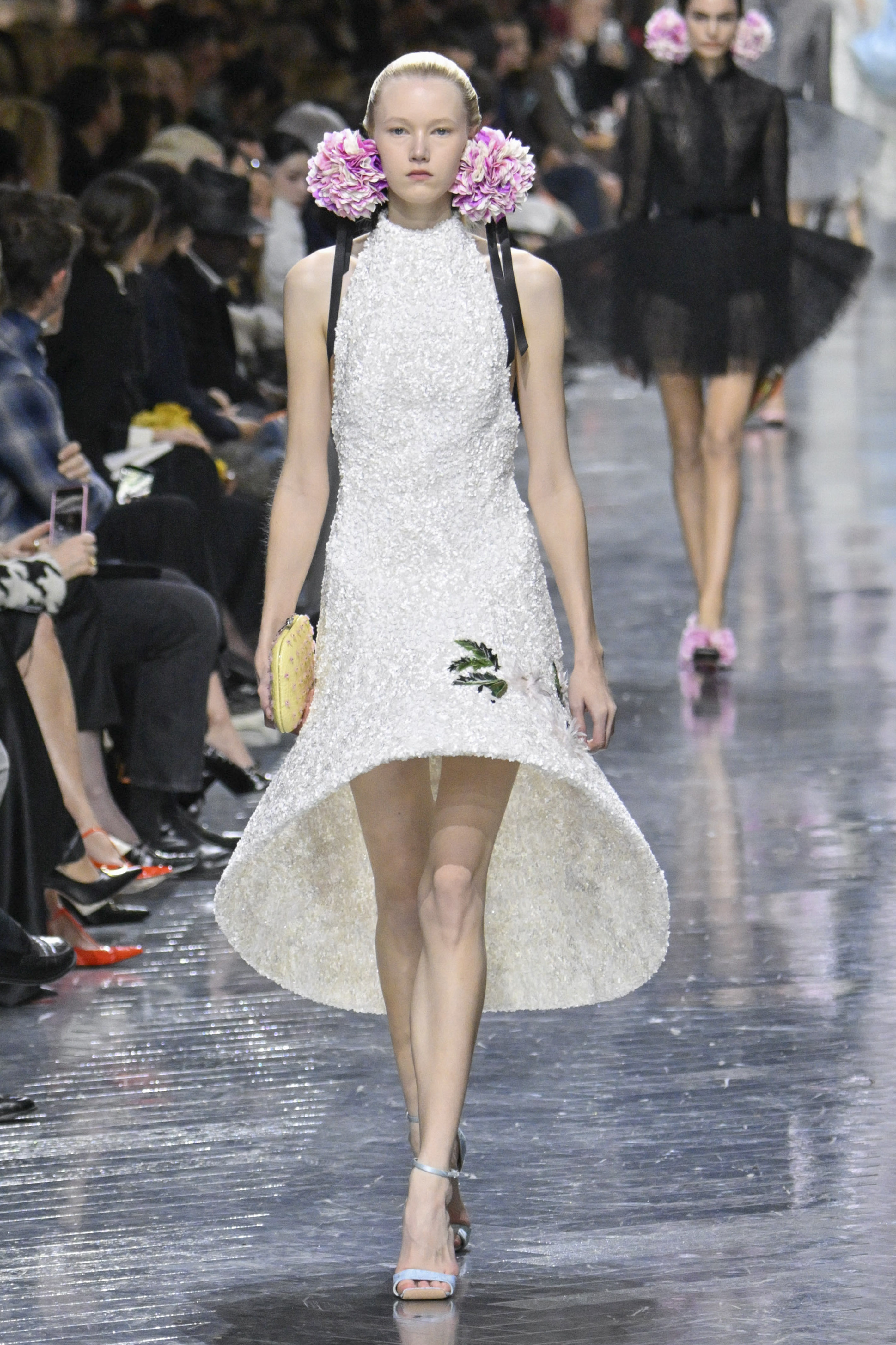 A model in a knee length white gown with a wipe hoop-like hem