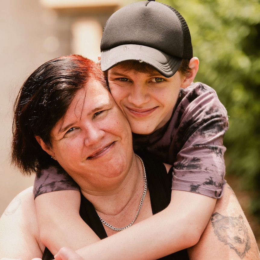 A young man hugging his Mum and smiling for the camera
