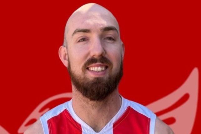 Grady with a beard in an AFL guernsy with a red background.
