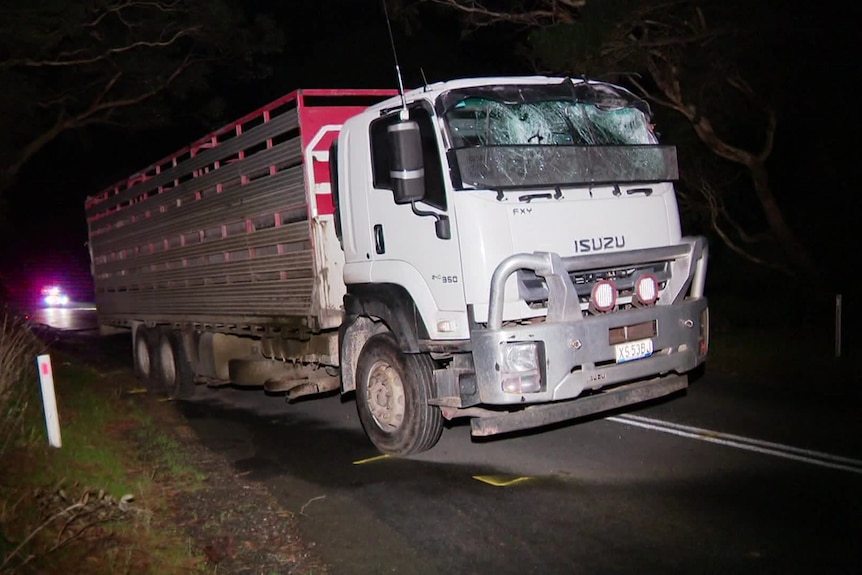 A stock truck with a shattered windscreen on the side of the road.