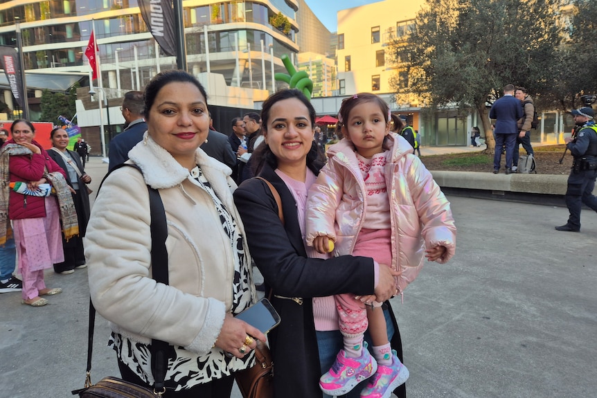 Two women, one holding a young girl, smile for the camera