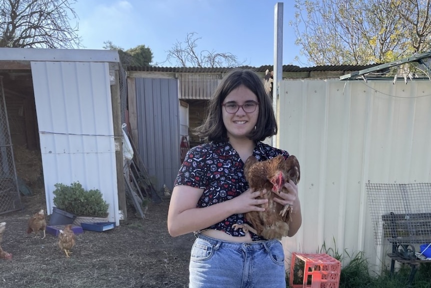 Girl in backyard holding a pet chicken.