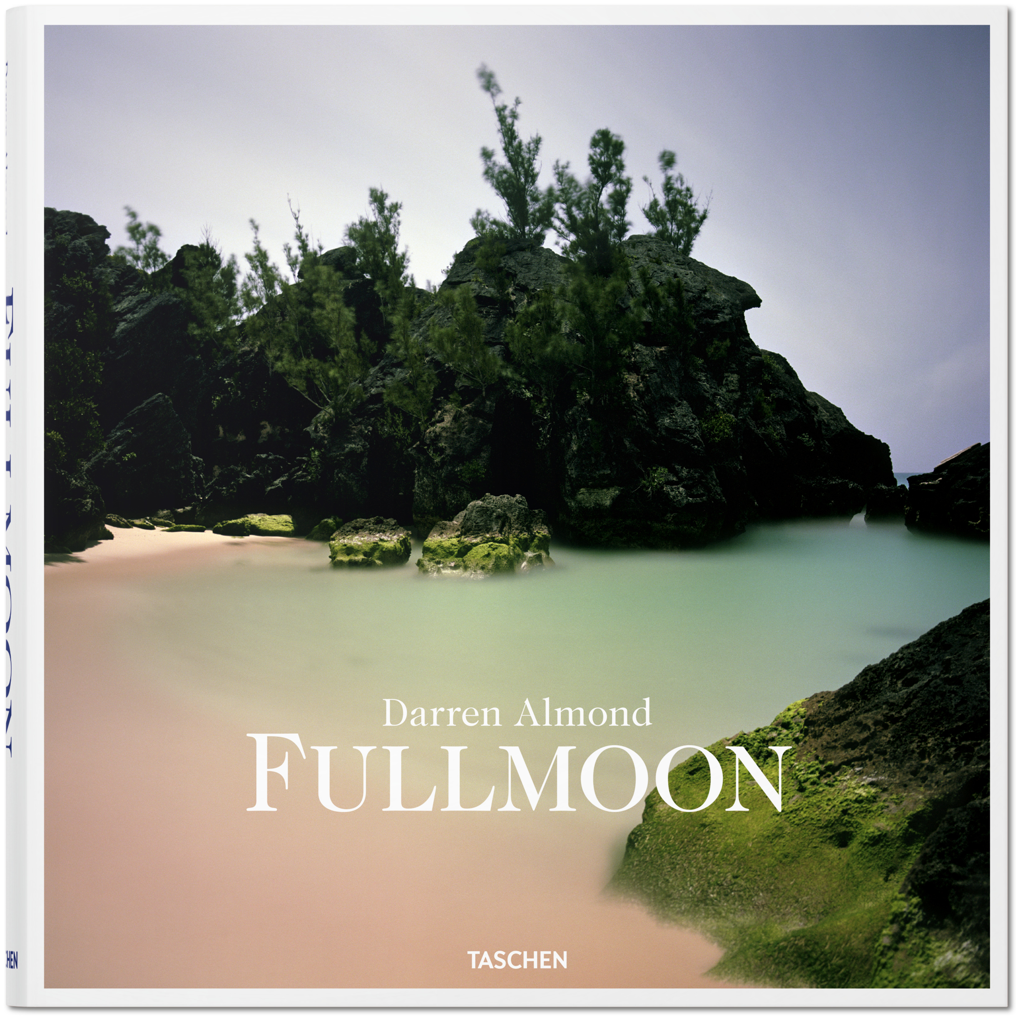 The square front cover of the Taschen book titled "Darren Almond FULLMOON," featuring a photograph of a rocky, tropical cove with pink sand and mint-green water.