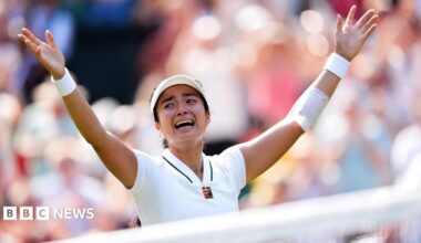 Filipina tennis player Alexandra Eala raises his arms after a Wimbledon match, net in front of her and a blurred image of the crowd in the background.