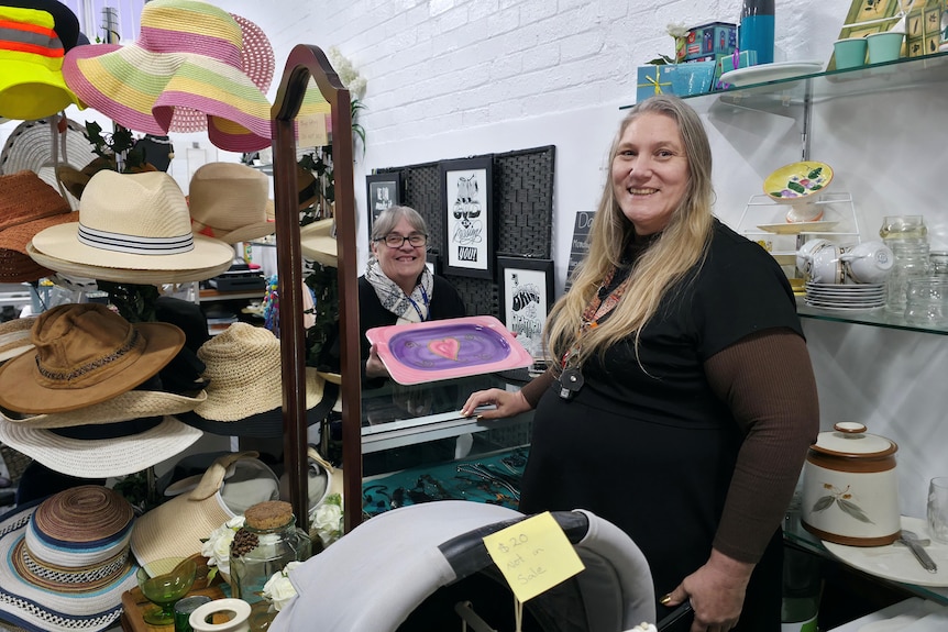 woman standing at counter with hats