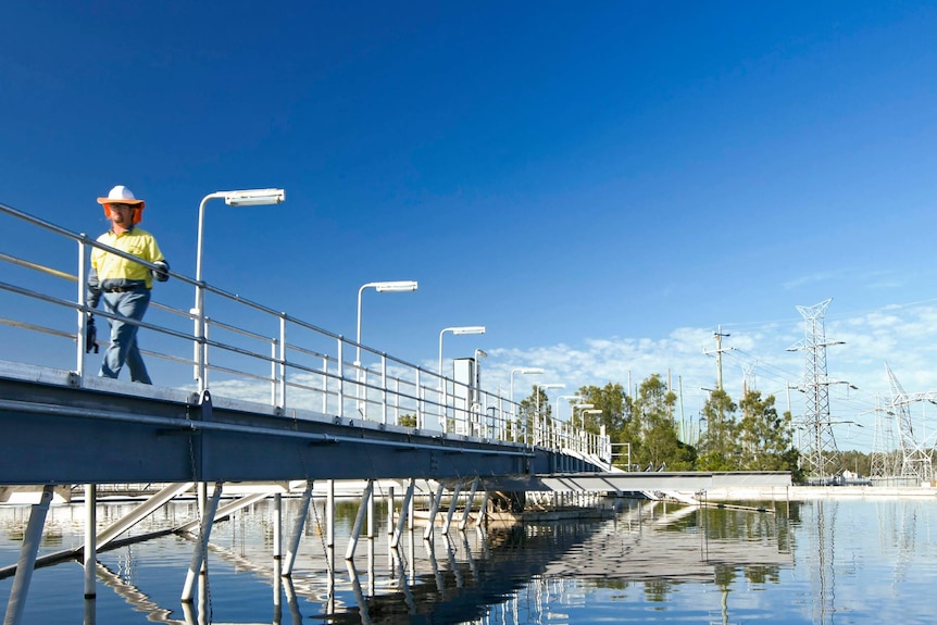 A man walks on a bridge over an Urban Utilities water storage