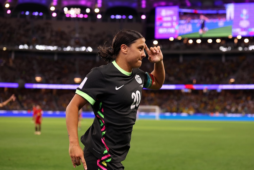 Matildas captain Sam Kerr smiles and points a finger to her head