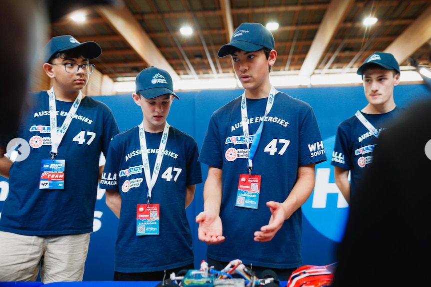 Four teenage boys wearing blue t-shirts and blue caps