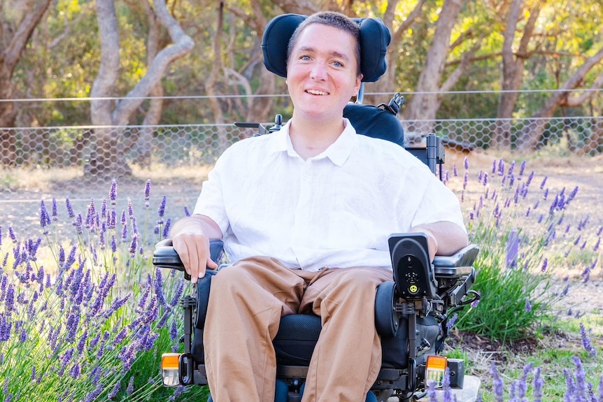 A smiling man in a wheelchair surrounded by lavender