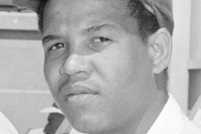 A black and white photo of a young man wearing a cricket cap
