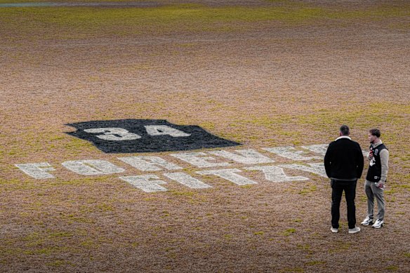 Matthew Fitzgerald (right) stands on Epping Football Club’s home ground, looking at a tribute to his brother Nathan, painted on the field.