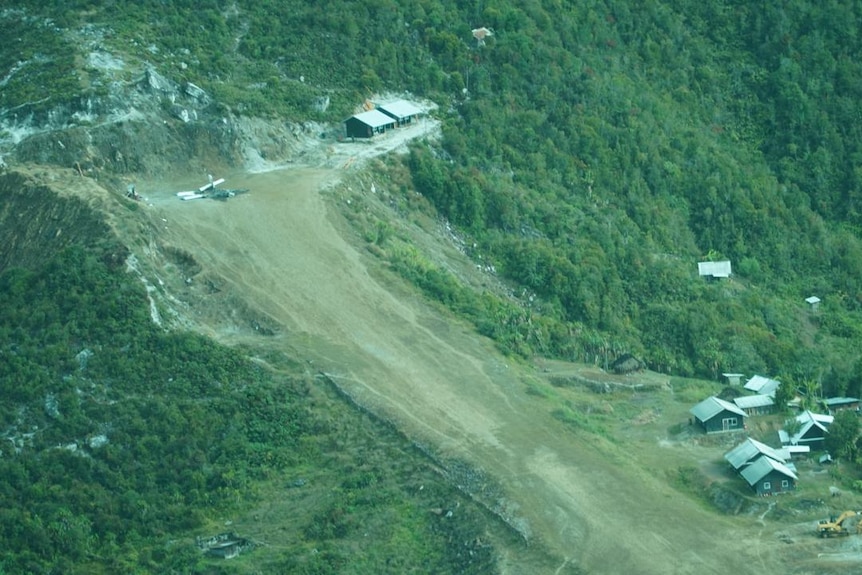 An aerial view of mountains, a steep road and buildings.
