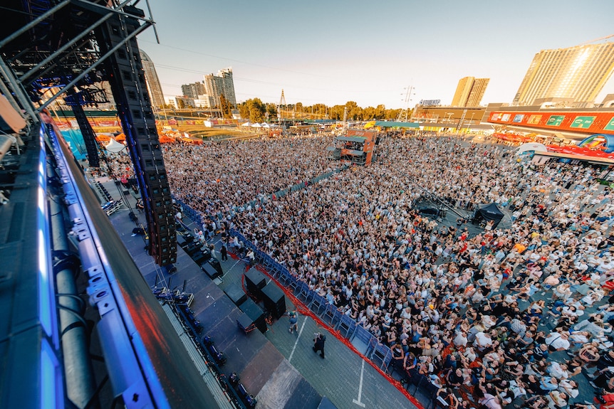 Thousands of people in a crowd at an outdoor stage ata music festival.