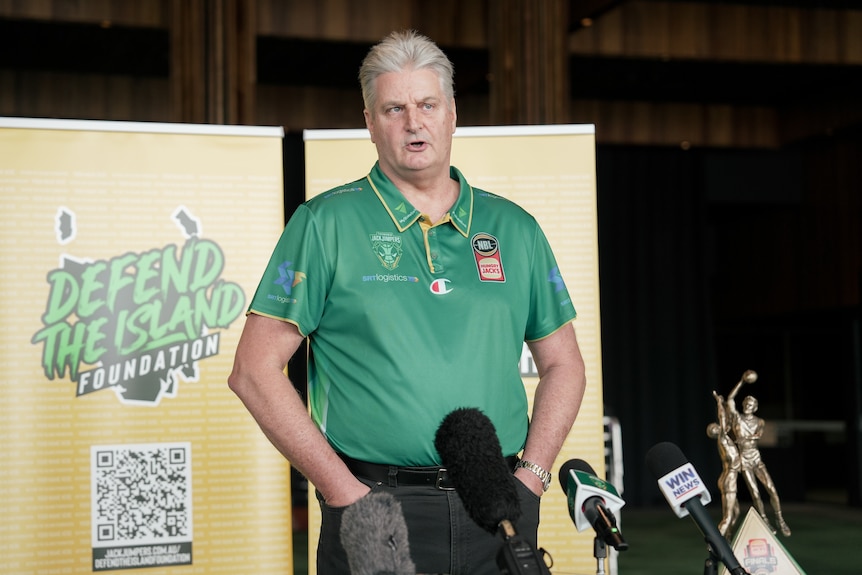 Man in green shirt speaking into microphones.