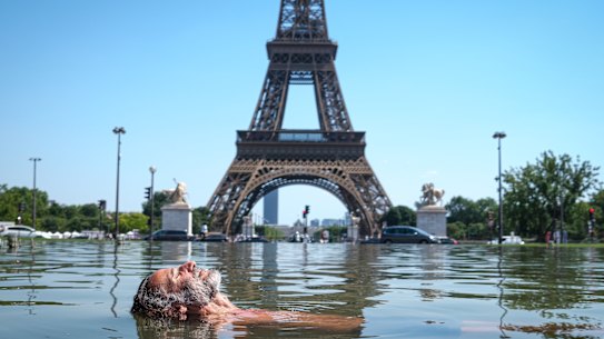A man cools off in the Warsaw Fountain at the Jardins du Trocadéro in front of the Eiffel Tower in Paris.
