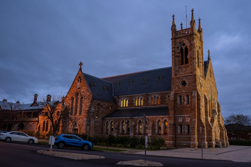 A large cathedral at night with lights glowing through some of the windows.