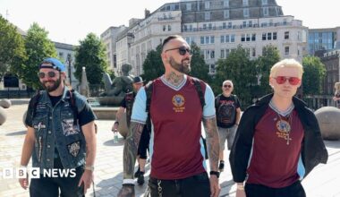 Three men wearing sunglasses, two wearing Aston Villa tops and a third wearing a denim jacket, gather in Victoria Square, Birmingham.
