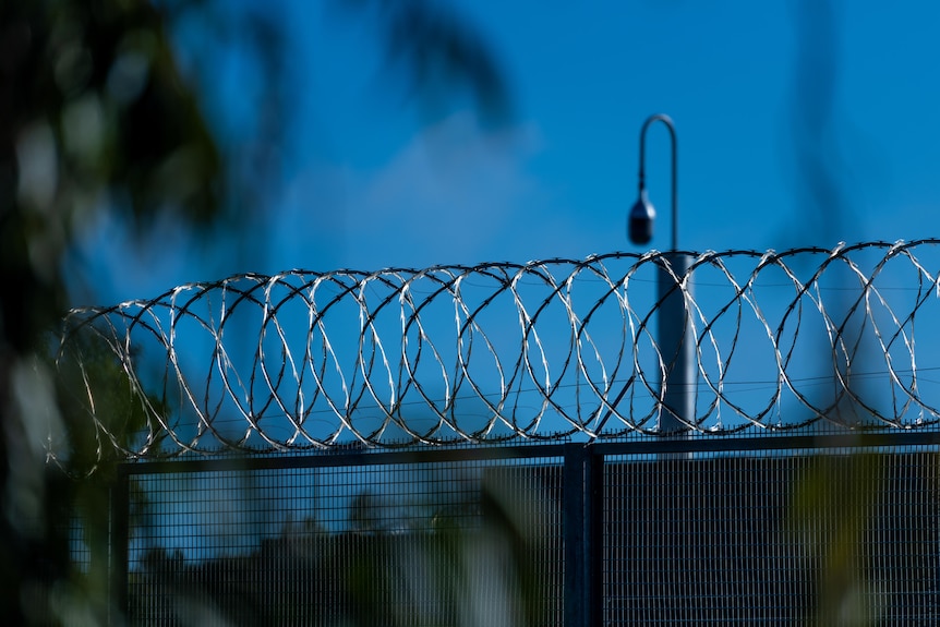 A barbed wire fence with a security camera in the background