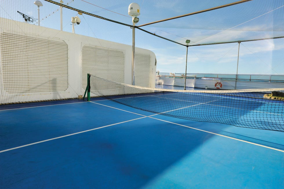 Oceania Cruises Padel outdoor tennis court with net and blue surface on a ship deck.