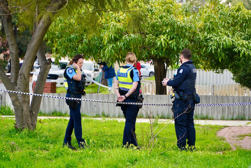 Police stand around on a lawn of a house