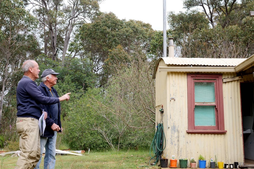Two men point at an old railway barracks